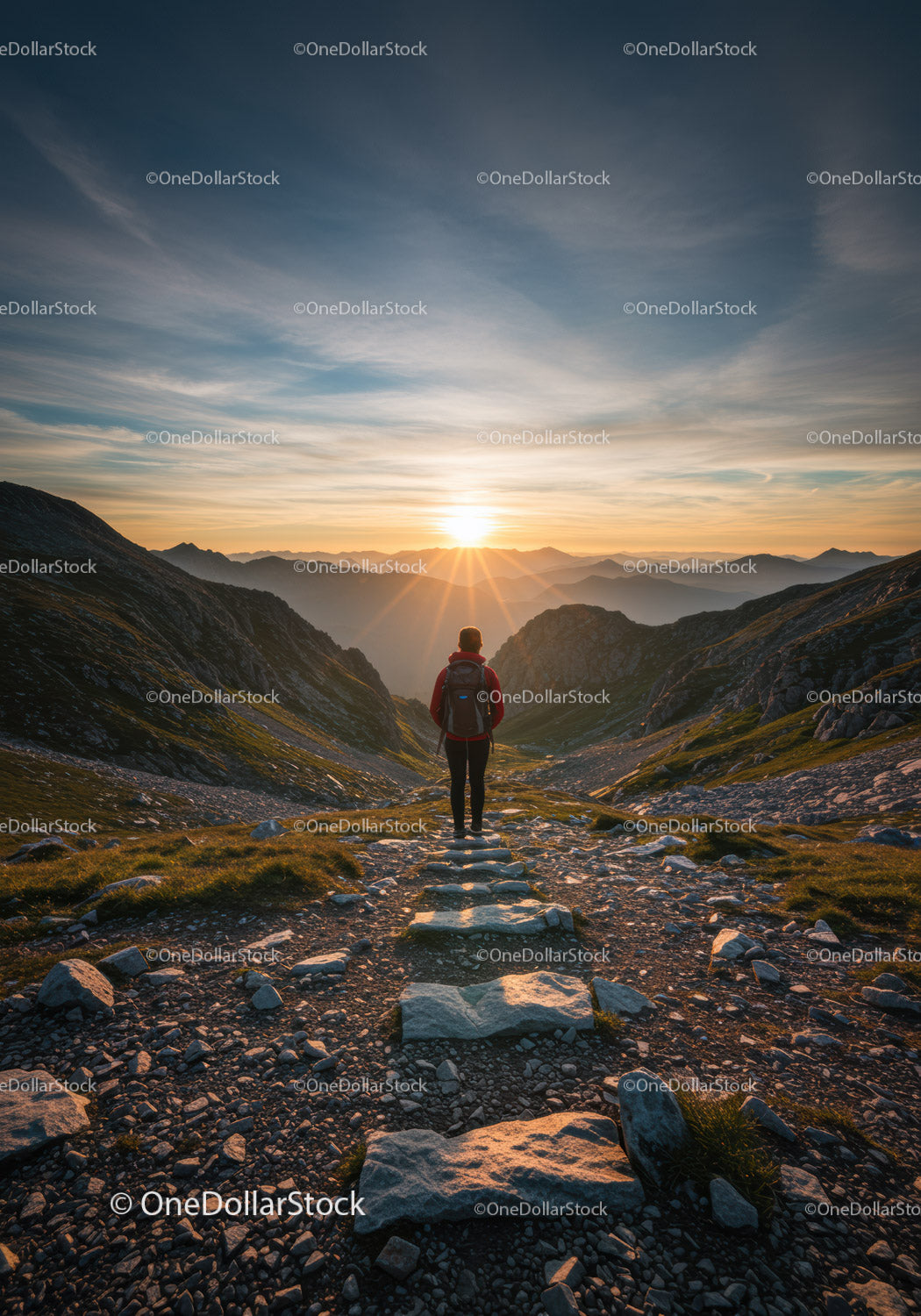 Hiker standing on rocky trail watching mountain sunset