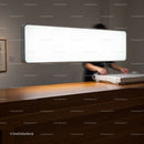 Person Wrapping Artwork on Wooden Counter Under Bright Light