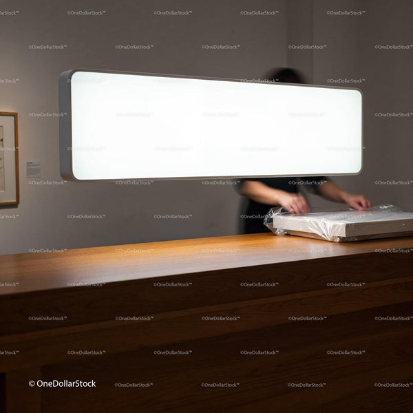 Person Wrapping Artwork on Wooden Counter Under Bright Light JPG Mockup Image