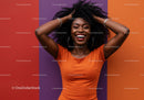Joyful Woman with Curly Hair in Orange Top Standing against Colorful Wall