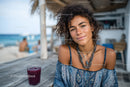 Young Woman Smiling at Beachside Café with Drink and Ocean View