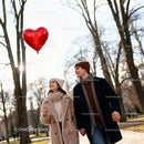 Young couple walking in park with heart balloon