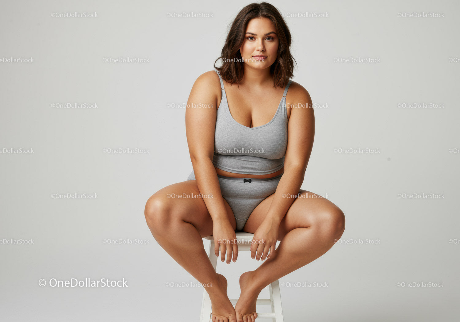 Confident Woman in Gray Casual Outfit Sitting on Stool in Studio