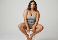 Confident Woman in Gray Casual Outfit Sitting on Stool in Studio