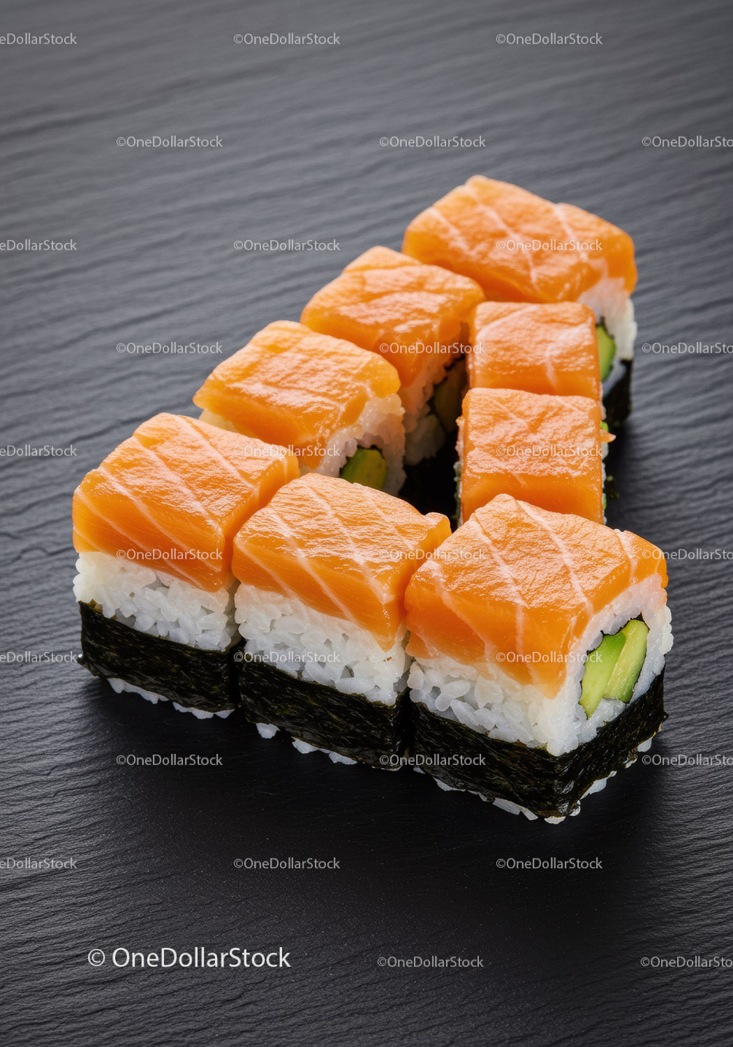 Fresh salmon sushi rolls with avocado on black slate