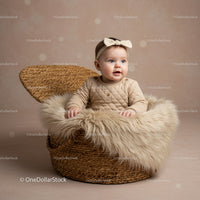 Adorable baby girl sitting in cozy wicker basket