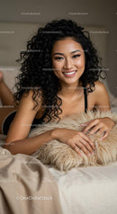 Smiling woman with curly hair relaxing on bed