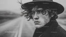 Young Man in Black Hat with Curly Hair in Rainy Urban Scene