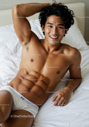 Smiling young man relaxing on bed in white underwear