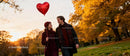 Couple walking in autumn park with heart balloon