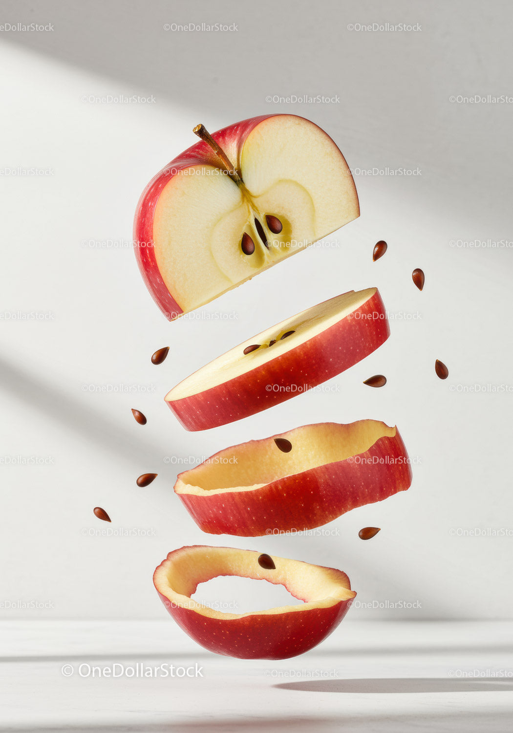 Floating sliced red apple with scattered seeds