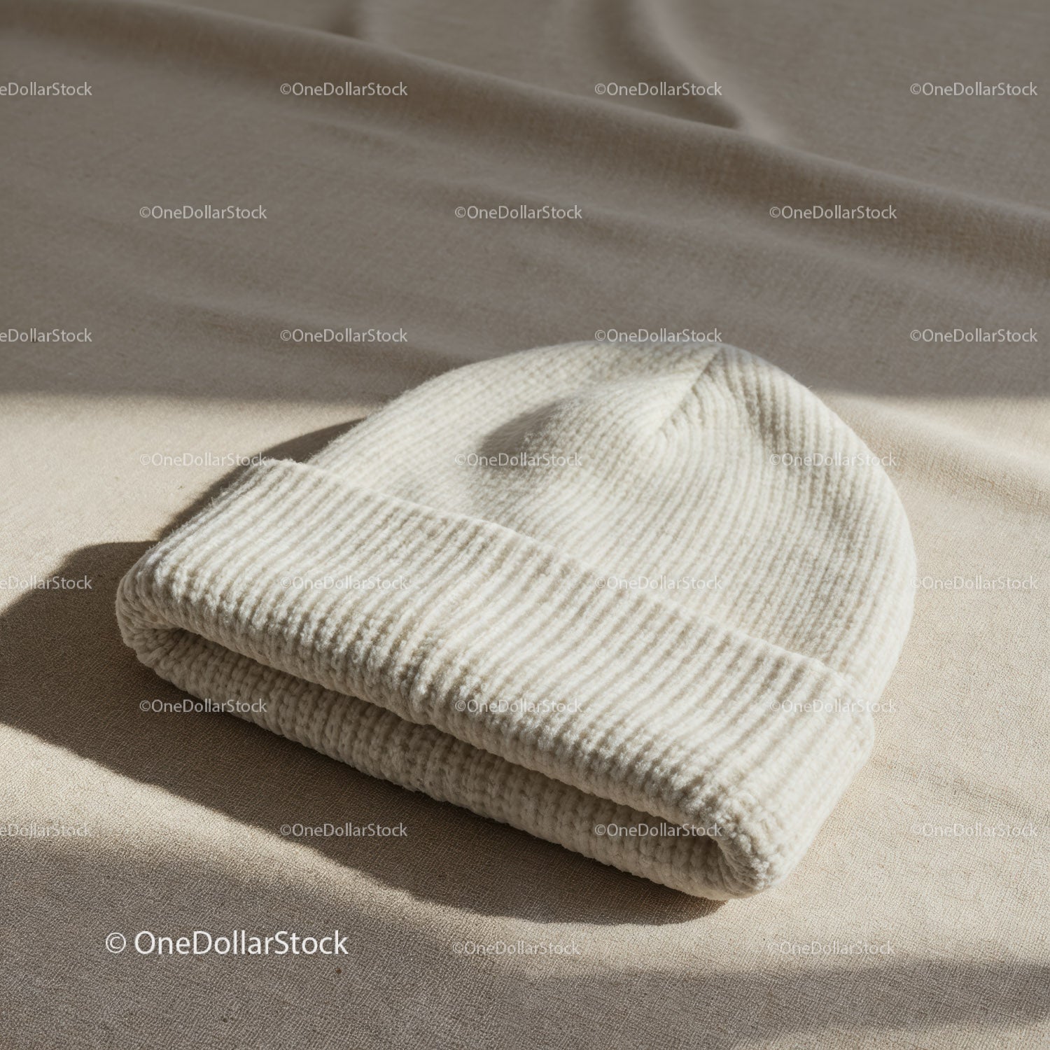 Miękka dzianinowa biała czapka beanie na beżowej powierzchni tekstylnej