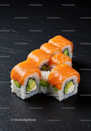 Salmon and avocado sushi rolls on dark slate surface