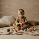Toddler Playing with Wooden Toys on Cozy Bed