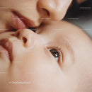 Tender moment of mother kissing newborn baby gently