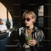 Stylish Woman with Sunglasses Holding Green Drink in Indoor Cafe