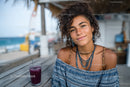 Young Woman Smiling at Beachside Cafe with Drink in Summer Vibes
