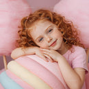 Smiling redhead girl resting on pastel marshmallow cushion