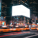 Busy city street with bright billboard and moving taxis