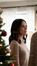 Thoughtful woman standing near Christmas tree indoors
