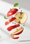 Red apple slices and seeds floating on white background
