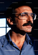 Thoughtful man with mustache and glasses indoors