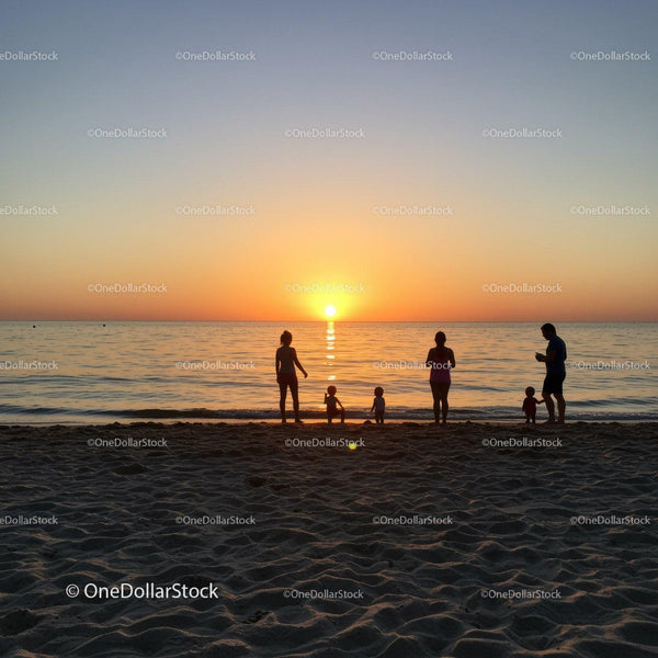 Silhouettes of a Family Enjoying Sunset on Sandy Beach at Dusk