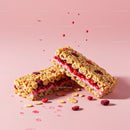 Crispy cereal bars with berry filling on pink background