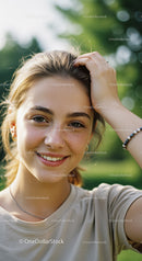 Young Woman Smiling Outdoors in Natural Light with Green Foliage