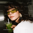 Stylish woman wearing yellow sunglasses and enjoying green drink