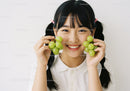 Cheerful Young Girl Holding Green Grapes with Bright Smile