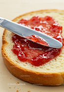 Fresh bread slice with strawberry jam and butter knife