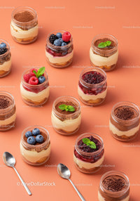 Assorted layered creamy desserts in jars with fresh berries