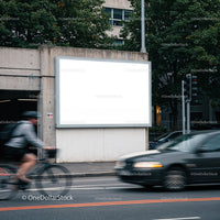 Blank urban billboard near busy street with cyclist and car