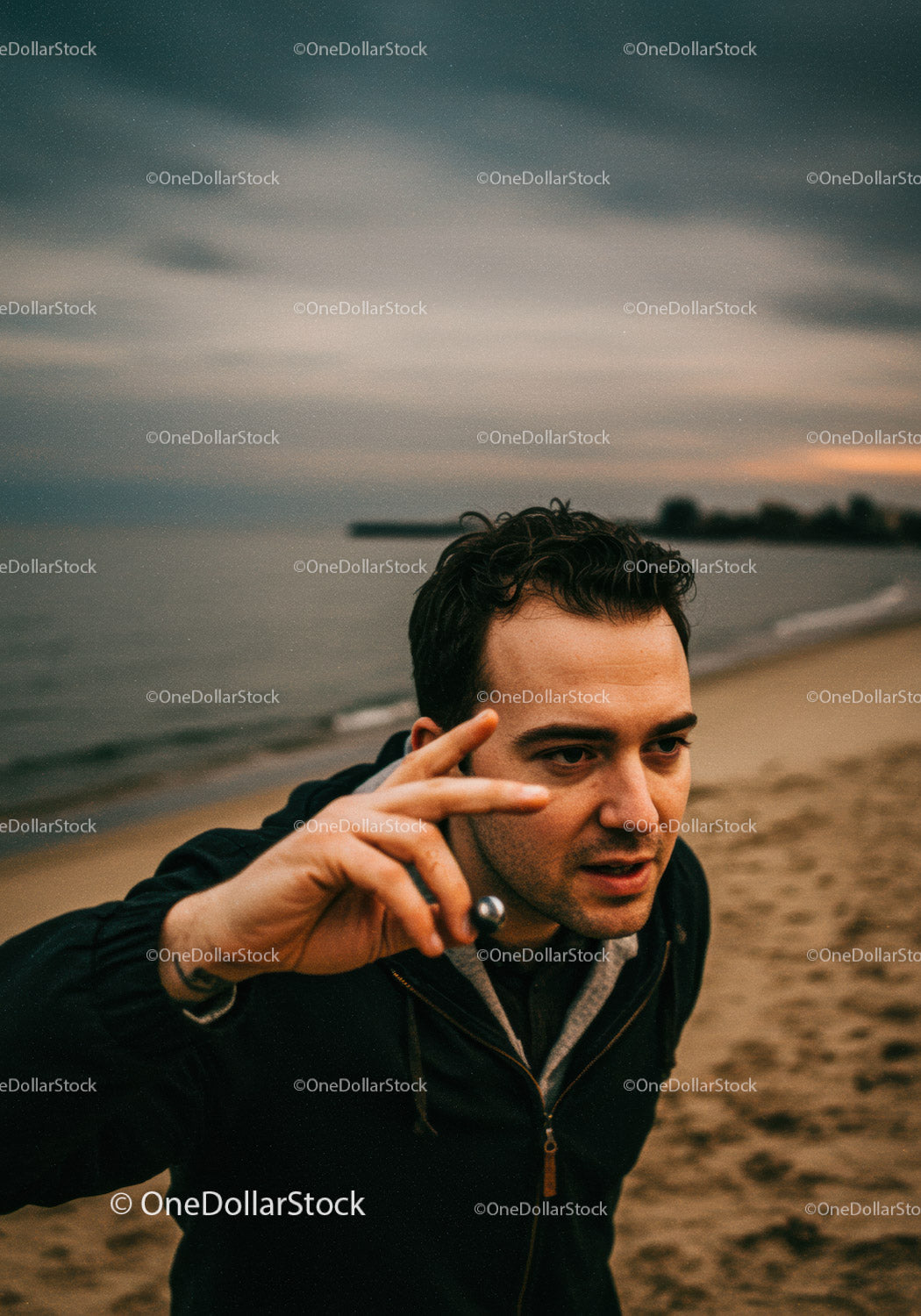Focused young man playing metal ball game on beach