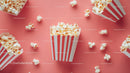 Popcorn in striped box on pink background for movie or snack themes