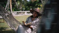 Woman Relaxing on Hammock in Tropical Garden Reading Book