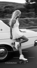 Young woman in white dress roller skating by vintage car