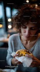 Woman Enjoying Juicy Cheeseburger in Cozy Modern Restaurant