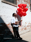 Man holding heart balloons and chocolates outdoors