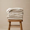Stack of Soft Beige Baby Blankets on Wooden Stool