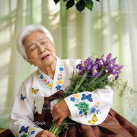 Elderly woman in traditional dress holding irises, emotional