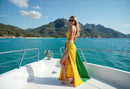 Stylish Woman in Bright Yellow and Green Dress on Yacht with Mountain View