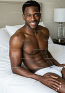 Smiling muscular man relaxing on bed in bright room