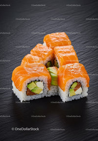 Fresh salmon avocado sushi rolls on black slate plate