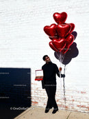 Man Holding Red Heart Balloons and Chocolates Outdoors