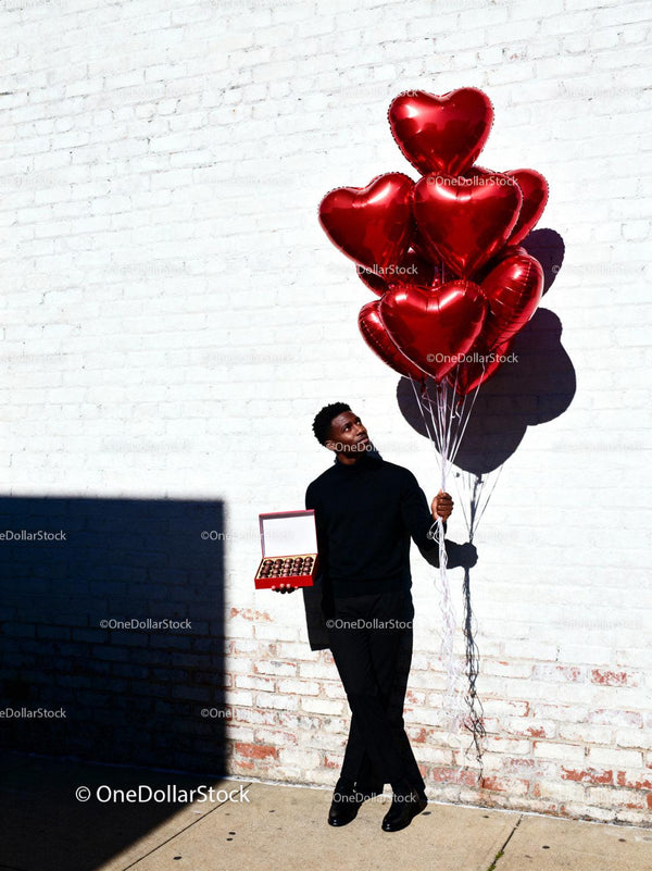 Man Holding Red Heart Balloons and Chocolates Outdoors