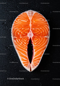 Fresh raw salmon steak on black textured surface