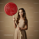 Young girl holding oversized red swirl lollipop