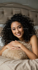 Smiling woman relaxing with soft pillow on bed